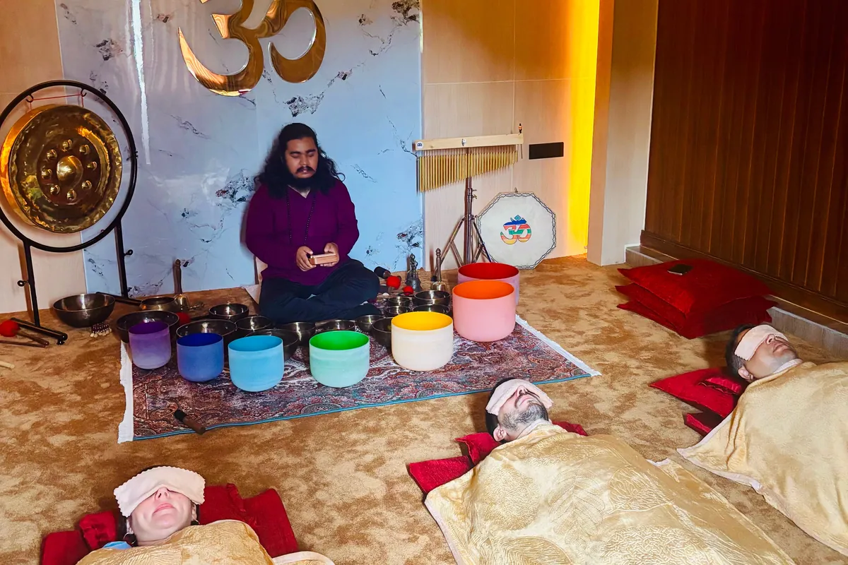 A sound healing session in progress, crystal singing bowls and gong laid out while guests rest under blankets