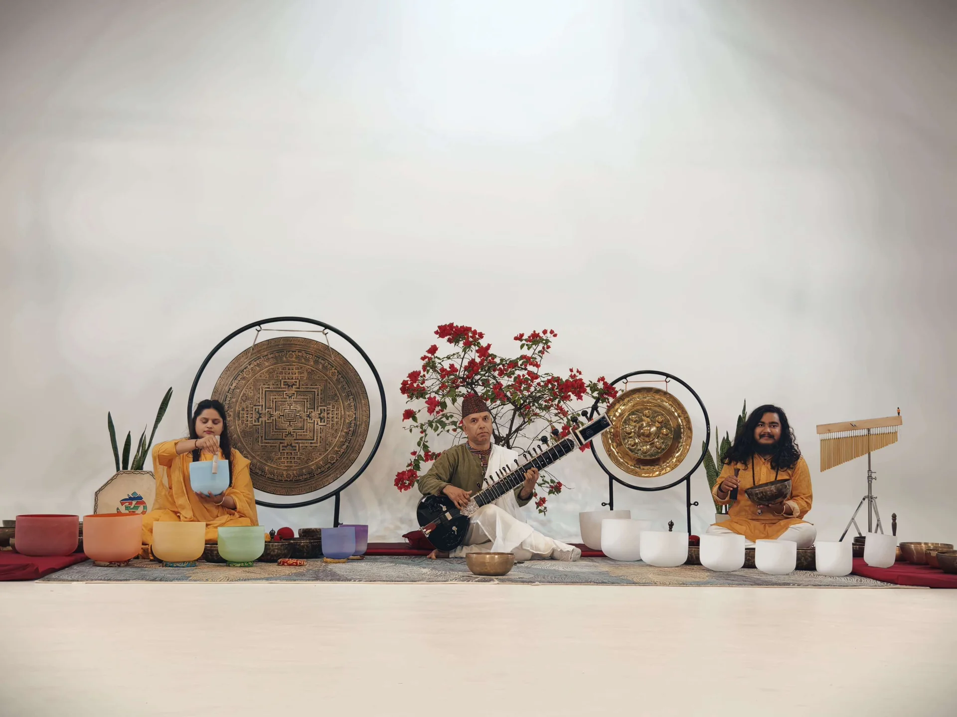 Gongs and crystal singing bowls set out in a bright practice room, two practitioners seated among them