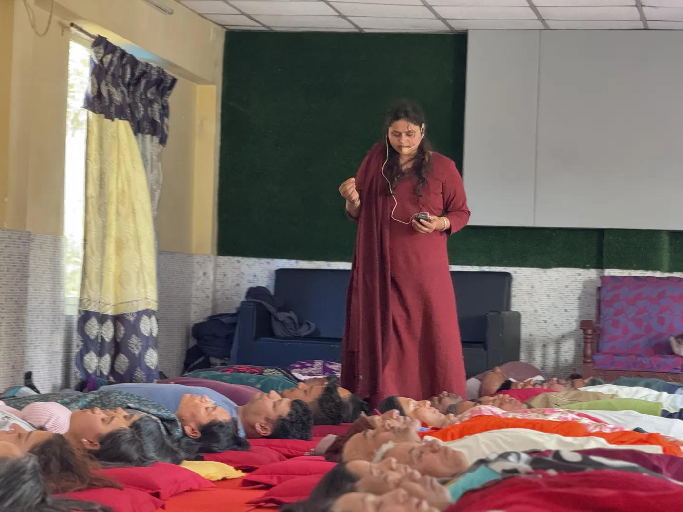 Maa Nisha Kabir guiding a hall of students through a group relaxation at Jivan Parivartan