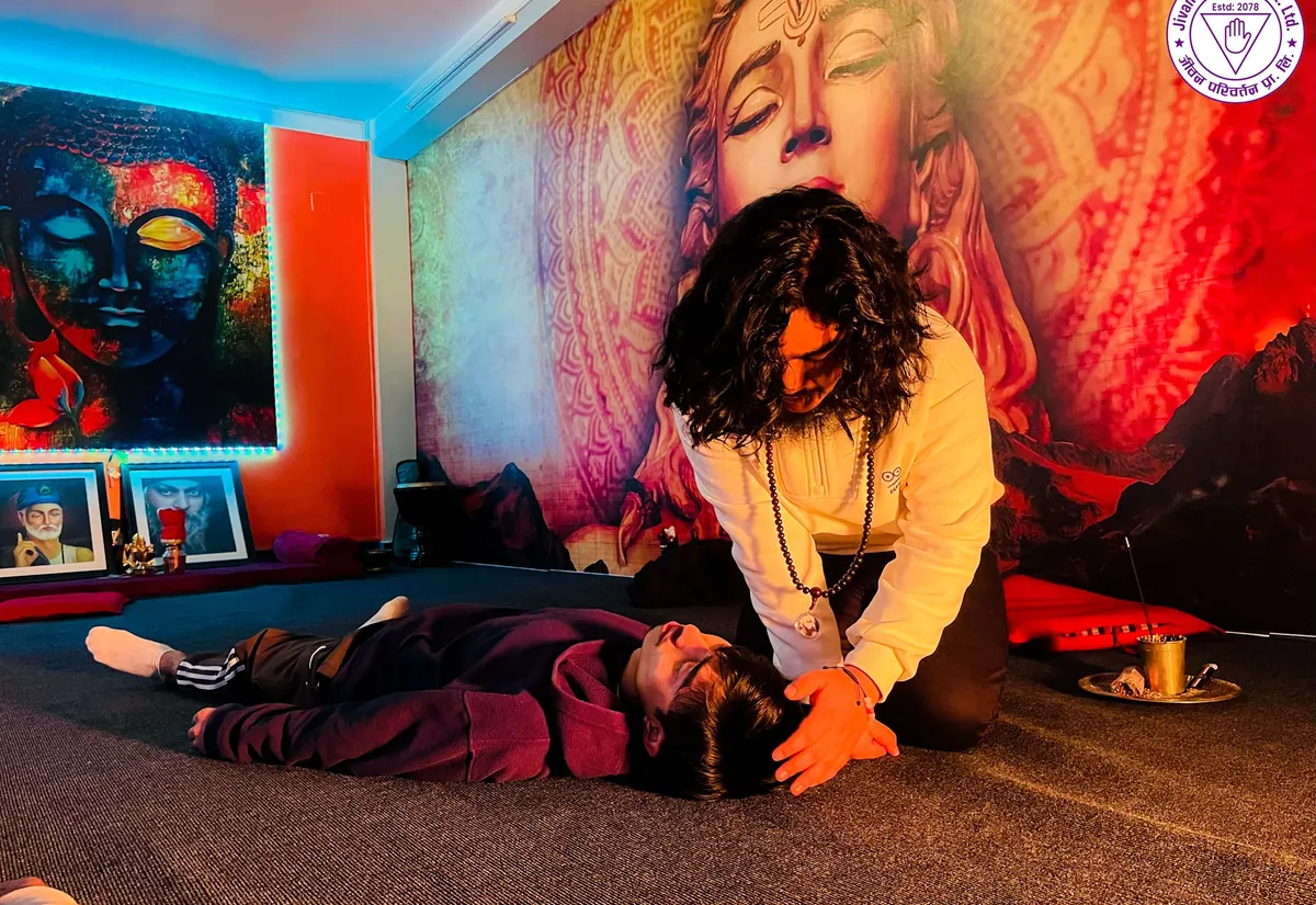A practitioner giving a one-to-one energy healing session to a guest resting on the floor at Jivan Parivartan