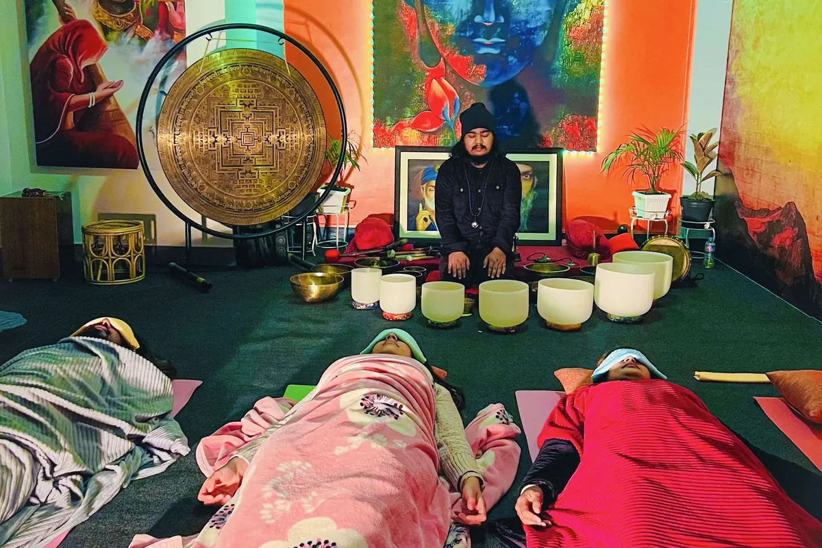 A sound healing session with gong and crystal singing bowls, guests resting under blankets