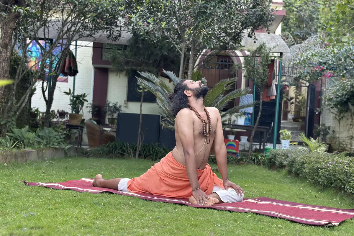 A teacher demonstrating a backbend on a mat in the garden during yoga training